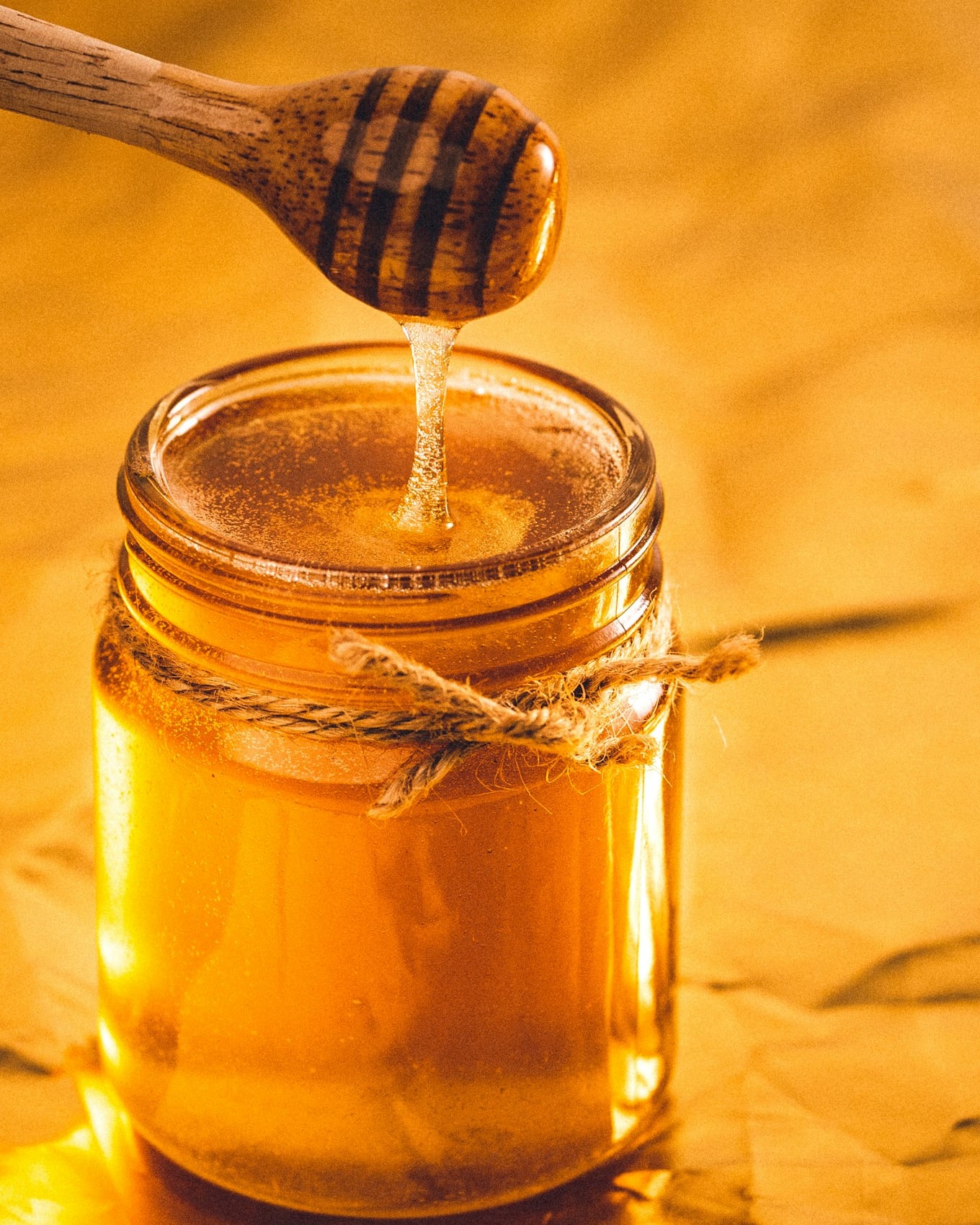 Miel doré coulant dans un bocal artisanal